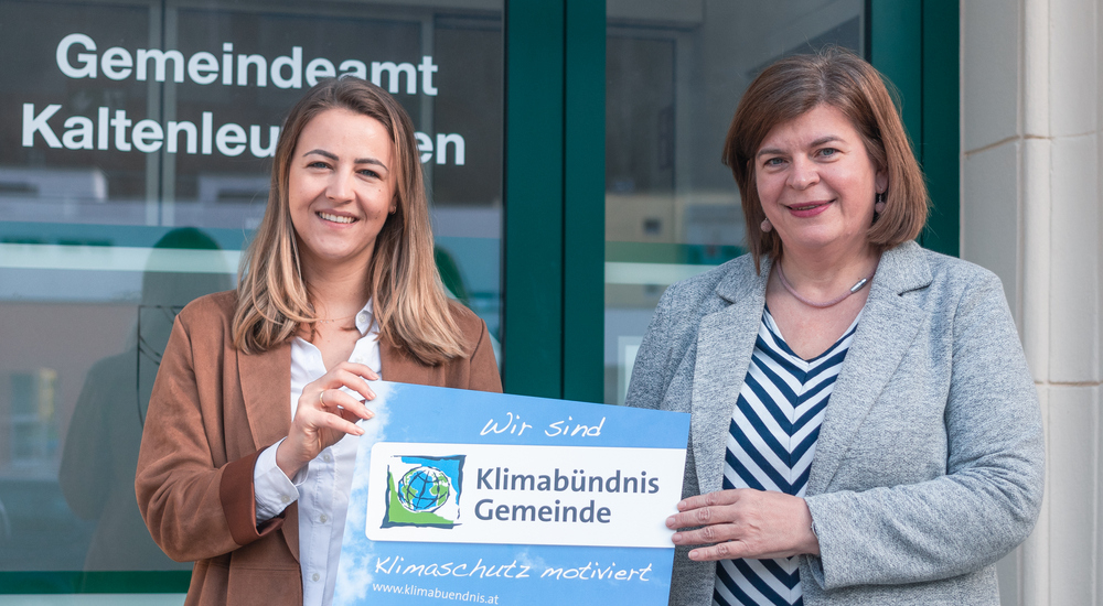 Bürgermeisterin Benadette Geieregger hält mit Petra Schön die Klimabündnis-Tafel vor dem Gemeindeamt.