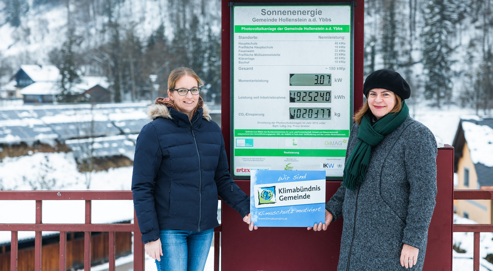 Petra Schön und Vorständin Manuela Zebenholzer mit der Klimabündnis-Tafel vor der Zählstation der PV-Anlagen.