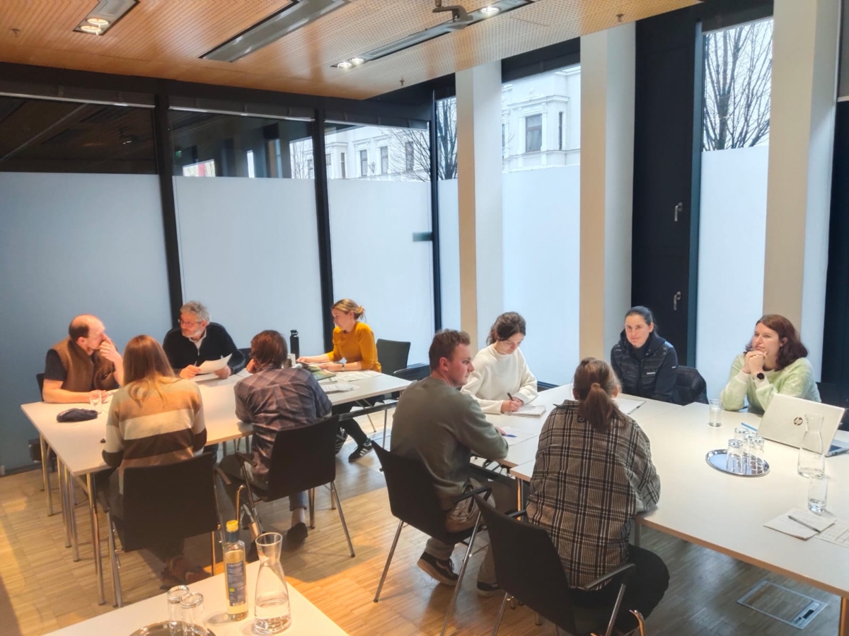 mehrere Menschen sitzen and Tischen zusammen und arbeiten und diskutieren