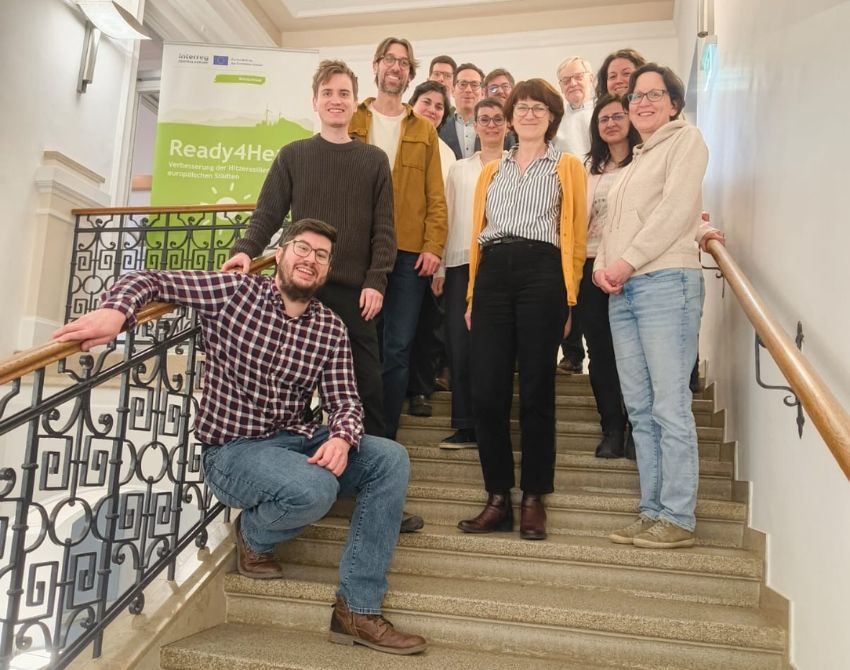 10 Personen posieren auf Stiege vor dem ready four heat banner und lächeln