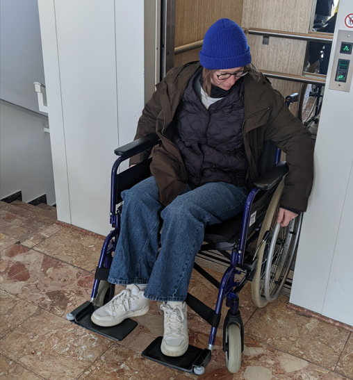 Frau in Rollstuhl kommt nicht durch die zu schmale Aufzugtür