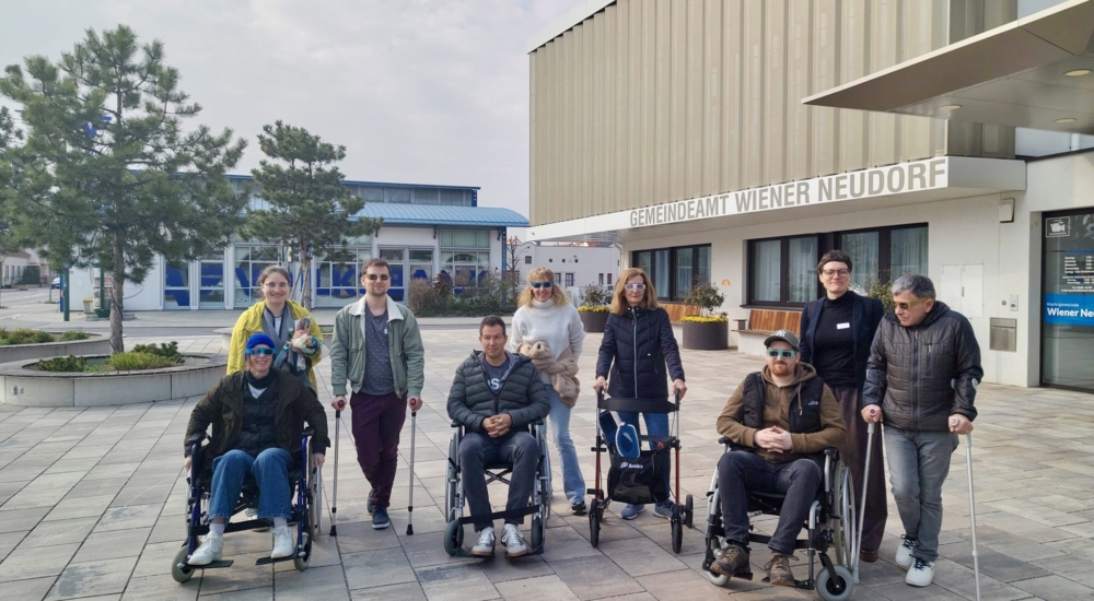Gruppe von Menschen mit Rollstühlen und Gehhilfen vor dem Gemeindeamt Wiener Neudorf