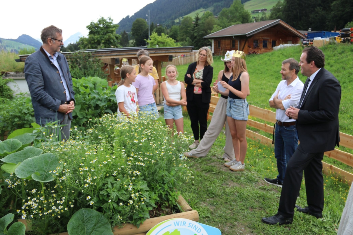 Kinder und Erwachsene unterhalten sich neben Hochbeeten